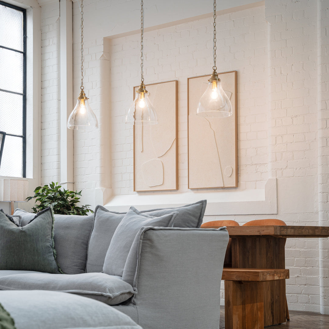 Living and dining room in a converted warehouse with satin brass pendants and white painted brick wall